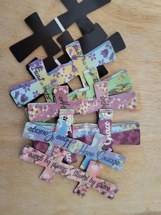 Decorative cross made of cut-out phrases and flowers on a wooden surface.